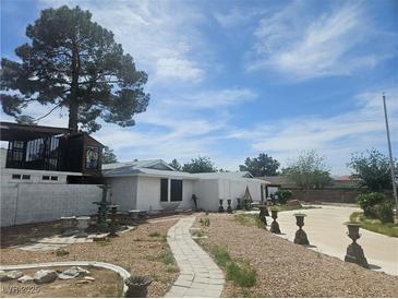 Single story home featuring unique yard art, neutral exterior and a walkway leading to the front door at 6215 Darby Ave, Las Vegas, NV 89146
