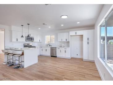 Bright kitchen boasts white cabinets, stainless steel appliances, and a large island with bar stool seating at 6420 Rosemount Ave, Las Vegas, NV 89156