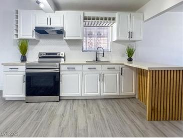 This remodeled kitchen features stainless steel appliances, white cabinets, and a charming wood-accented peninsula at 1608 E Mcdonald Ave, North Las Vegas, NV 89030