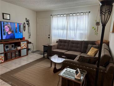 Inviting living room featuring a comfortable brown sofa and a large flat-screen TV at 2136 Bavington Dr # A, Las Vegas, NV 89108