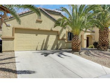 Inviting single-story home with a two-car garage, complemented by palm trees and desert landscaping at 520 Blackbird Knoll Ct, North Las Vegas, NV 89084