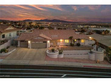 Inviting single-story home featuring a terra cotta roof, desert landscaping, and attached two-car garage at sunset at 1060 Calico Ridge Dr, Henderson, NV 89011