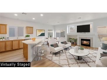 Open-concept living room with a modern fireplace, a breakfast bar, and light hardwood flooring at 7936 Pinnochio Ave, Las Vegas, NV 89131