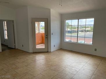 Bright living room featuring tile floors, a large window, and a glass door leading to a balcony at 1830 N Pecos Rd # 252, Las Vegas, NV 89115