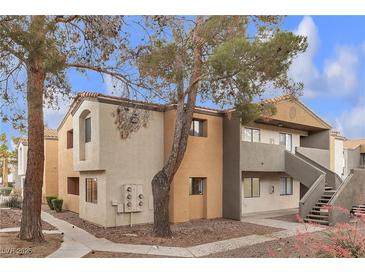 Two-story townhouse showcases neutral tones, complemented by mature trees and walkway access at 3151 Soaring Gulls Dr # 1179, Las Vegas, NV 89128