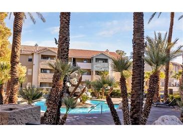 Inviting community pool area featuring palm trees, a rock waterfall, and comfortable lounge chairs at 4200 S Valley View Blvd # 3053, Las Vegas, NV 89103