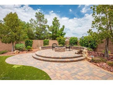 Inviting backyard with brick patio, stone fire pit, seating, and lush landscaping offers space for relaxation at 8340 Jeremiahs Lodge Ave, Las Vegas, NV 89131