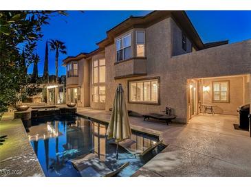 A private backyard pool with lounge seating, a fire pit and lush landscaping is perfect for outdoor living at 10671 Capesthorne Way, Las Vegas, NV 89135