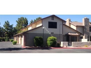 Two-story townhouse featuring a tan exterior with brick accents and a well-maintained landscape at 3232 Dayflower St # 4, Las Vegas, NV 89121