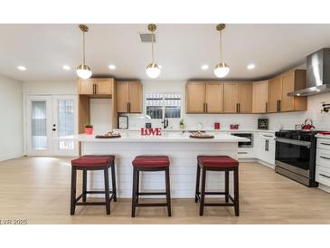 Bright kitchen features white cabinets, large island with seating, modern appliances, and stylish pendant lighting at 4237 E Twain Ave, Las Vegas, NV 89121