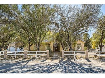 Charming single-story home with mature trees, desert landscaping, and a white fence at 6325 Guy Ave Ave, Las Vegas, NV 89131