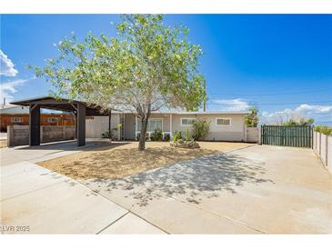 Charming single-story home featuring a covered carport, gravel yard, and mature landscaping under a bright blue sky at 67 Oklahoma Dr, Henderson, NV 89015