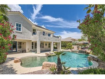 Beautiful backyard pool with a rock waterfall and lush landscaping in a luxury home at 3042 Hammerwood Dr, Las Vegas, NV 89135