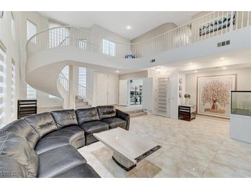 Spacious living room features a spiral staircase, tile flooring and a large leather sofa at 3192 Tullio Way, Henderson, NV 89052