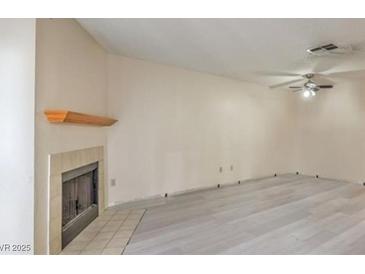 Cozy living room with modern flooring, neutral walls, fireplace, and a ceiling fan at 6861 Tamarus St # 203, Las Vegas, NV 89119