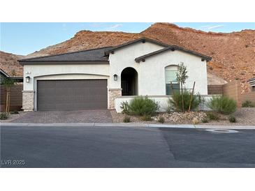 Charming single-story home featuring desert landscaping, a brick driveway, and a two-car garage at 80 Cathedral Wash Pl, Henderson, NV 89011
