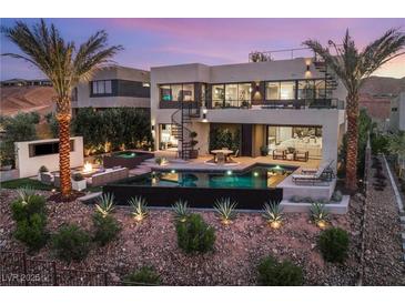 Stunning backyard featuring a pool, spa, lounge area, fire pit, and lush landscaping with palm trees at 12 Desert Lake Ln, Henderson, NV 89011