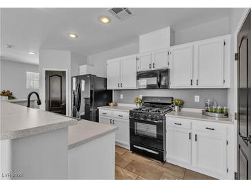 Well-lit kitchen features white cabinets, black appliances, and modern countertops at 1346 Crystal Hill Ln # 3, Henderson, NV 89012