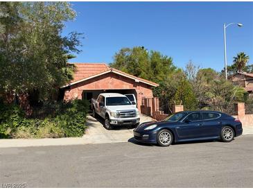 Charming single-story home with a tile roof and two cars parked in the driveway on a sunny day at 3167 El Cedro Cir, Las Vegas, NV 89121