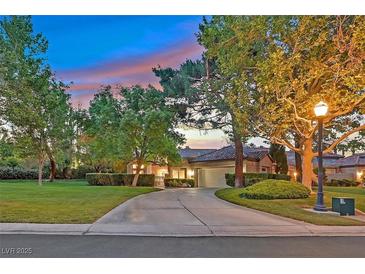 Inviting home exterior with a lush lawn, mature trees, and a circular driveway leading to an attached two-car garage at 8370 Plum Creek Ct, Las Vegas, NV 89113