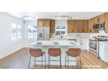 Bright kitchen features a white island with bar stool seating, wood cabinets, and stainless steel appliances at 1600 E Mcdonald Ave, North Las Vegas, NV 89030
