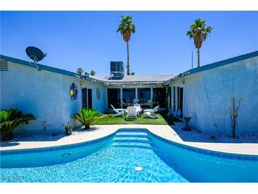 Inviting pool with palm trees and patio area, perfect for outdoor relaxation and entertaining in the backyard at 3030 Liberty Cir, Las Vegas, NV 89121