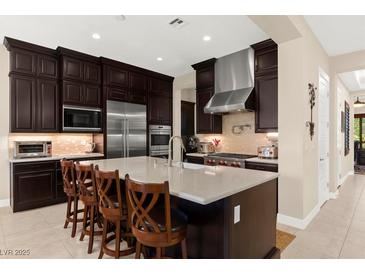 A gourmet kitchen features a large island, stainless appliances, and dark wood cabinetry at 6810 Silver Crescent St, Las Vegas, NV 89148