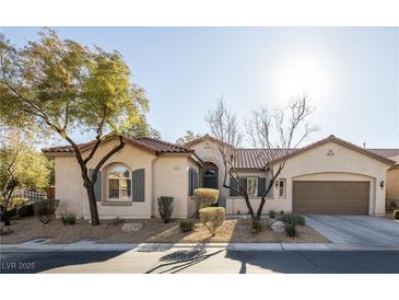Charming single-story home with desert landscaping and a two-car garage, complemented by mature trees and a blue sky at 9077 Creed Mountain Pl, Las Vegas, NV 89178