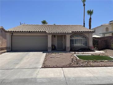 Charming single-story home featuring a well-manicured front yard and a two-car garage and tile roof at 1468 Harmony Hill Dr, Henderson, NV 89014