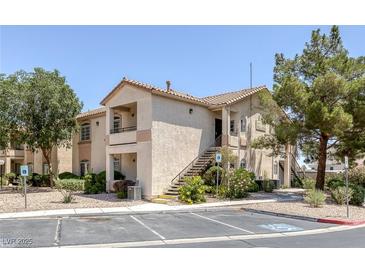 Attractive two-story condo building featuring beige stucco, a tile roof, and staircase access to upper units at 1830 N Buffalo Dr # 2024, Las Vegas, NV 89128