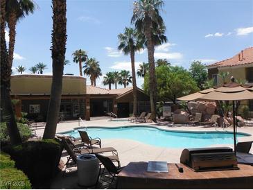 Resort-style swimming pool with palm trees, lounge chairs, and grilling area creating a relaxing community space at 2120 Ramrod Ave # 417, Henderson, NV 89014