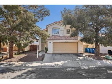 Charming two-story home featuring a beige exterior, two-car garage, and mature landscaping with shade trees at 5636 Royal Castle Ln, Las Vegas, NV 89130