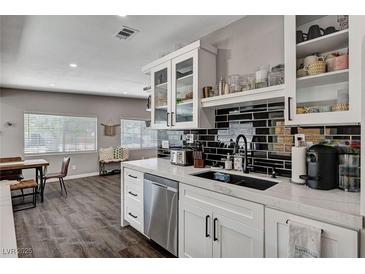 This kitchen features white cabinets, stainless steel appliances and a black tiled backsplash at 3013 Roseville Way, Las Vegas, NV 89102