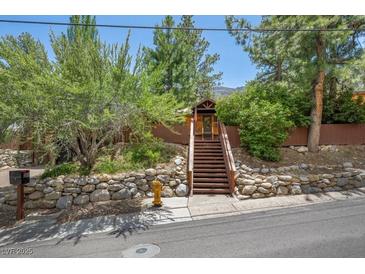Charming home featuring mature trees, a rock wall, and a welcoming staircase to the front entrance at 3935 White Fir Way, Mount Charleston, NV 89124