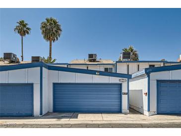View of exterior featuring two-story home with a blue garage door, palm trees, and clear skies at 4259 Kona Coast Way, Las Vegas, NV 89121