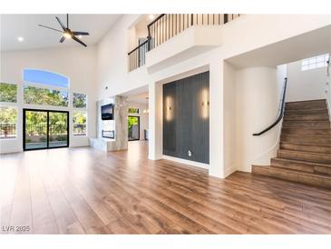 Bright living room with hardwood floors, fireplace, high ceilings and expansive windows with backyard view at 912 Pro Players Dr, Las Vegas, NV 89134