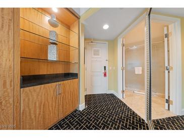 Condo hallway with decorative shelving, white door, and bathroom entrance featuring patterned black and white carpeting at 2000 N Fashion Show Dr # 2704, Las Vegas, NV 89109