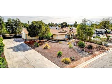Lovely single-story home featuring a xeriscaped front yard with mature shade trees and a long driveway leading to a two-car garage at 4343 Sharpshooter Ln, North Las Vegas, NV 89031