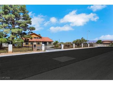 Charming home with a secure gated entrance and lush green trees, offering both privacy and curb appeal at 1385 Morning Sun Way, Las Vegas, NV 89110
