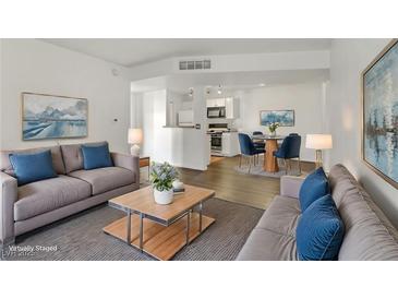 Bright living room with hardwood floors, neutral walls, couches, dining area, and updated kitchen at 2120 Ramrod Ave # 1318, Henderson, NV 89014