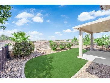 Beautiful backyard features green turf, desert landscaping, and a covered patio with ample space for relaxing at 2504 Libretto Ave, Henderson, NV 89052