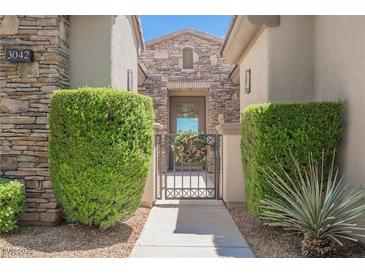 Charming front entrance featuring a stone facade, decorative shrubs, and an inviting wrought iron gate at 3042 Soft Horizon Way, Las Vegas, NV 89135
