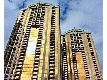 Low angle view of two luxury high-rise condo buildings with gold-tinted windows against a cloudy sky at 125 E Harmon Ave # 1918, Las Vegas, NV 89109