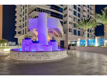 Nighttime view of the condo building entrance, featuring a water feature with purple lights and manicured landscaping at 2700 Las Vegas Blvd # 1804, Las Vegas, NV 89109