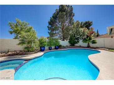 Inviting backyard pool surrounded by lush landscaping and mature trees provides a tranquil outdoor retreat at 9333 Dry Dock Dr, Las Vegas, NV 89117