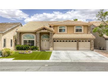 Inviting two-story home featuring a three-car garage, manicured lawn, and stone accents at 3692 River Canyon Rd, Las Vegas, NV 89129