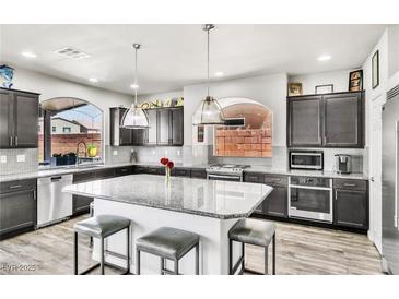 Modern kitchen boasts granite countertops, stainless appliances, and a large center island with seating at 5976 Rockway Glen Ave, Las Vegas, NV 89141