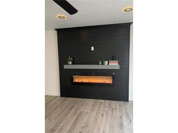 Living room features a black accent wall with modern electric fireplace and wood-look flooring at 8068 Cetus Cir, Las Vegas, NV 89128