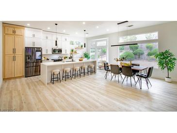 Modern kitchen featuring a large island with bar seating and stainless steel appliances in an open floor plan at 10709 Hunters Woods Pl, Las Vegas, NV 89134