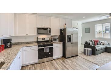 Modern kitchen features white cabinets, granite countertops, and stainless steel appliances at 1611 Prairie Fields Ct, Las Vegas, NV 89115